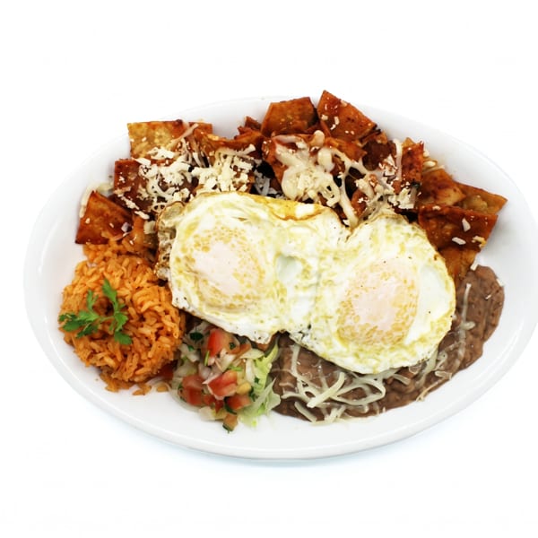 Plate of chilaquiles with two fried eggs, rice, refried beans, and pico de gallo.